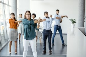 A group of workers boost employee morale and productivity through stretches and physical fitness.